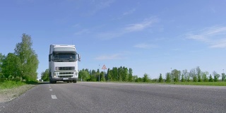 十八辆卡车开在空旷的乡村公路上，经过摄像头，车轮旋转。