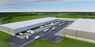 航拍工业仓库/仓库大楼/装卸区，其中有多辆货车在装卸货物。