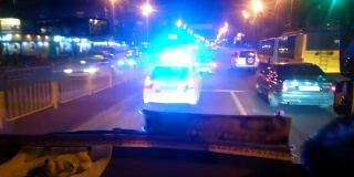 警察巡逻车夜间行驶在城市街道上，执法者值班，维护公共秩序