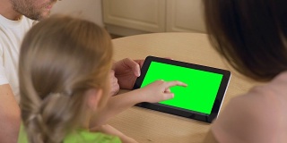 幸福的家庭使用平板电脑上的应用程序与预按键绿色触摸屏