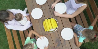 俯视图的家庭享受户外晚餐吃煮玉米棒子