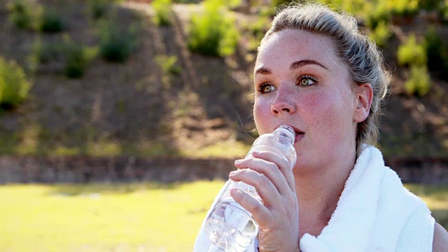 女人在锻炼后边喝水边擦汗