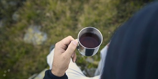 夏日户外日出时，年轻人在山上用金属杯喝茶