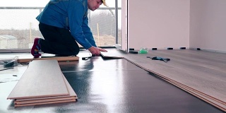 成年男性工人安装强化地板，浮木瓷砖