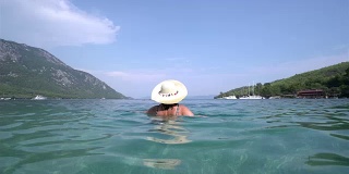 中年妇女戴着帽子，跳进海里。Marmaris土耳其