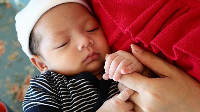 妈妈用手摸着睡着的宝宝的手