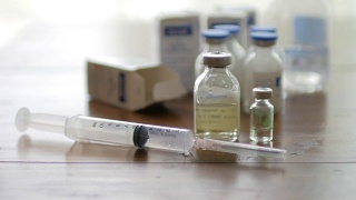 注射疫苗注射器与小瓶医疗近距离白色背景和木制桌子视频素材模板下载