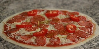 在披萨上倒橄榄油。意大利腊肠、胡椒、奶酪和橄榄油的披萨