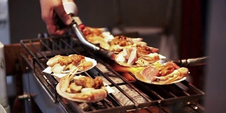 日本筑地市场的贝壳海鲜烧烤。厨师使用烧过的火炬