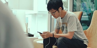 亚洲十几岁的男孩在手机上听音乐耳机。