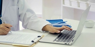 中年亚洲女性药剂师在药店工作时使用笔记本电脑