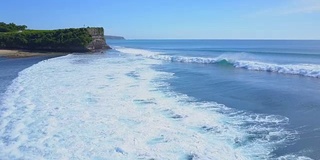 空中，特写:大而美丽的管波接近巴厘岛海滩上的人们