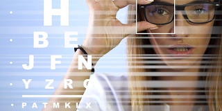 可爱的年轻成年褐发女人戴眼镜在诊所检查她的视力