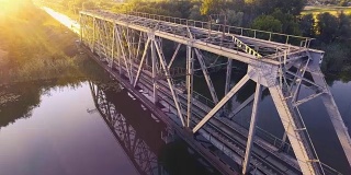 日落时分，一列高速列车驶过河上的一座桥