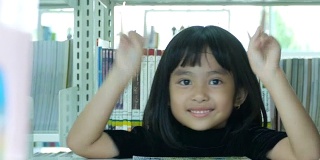 图书馆里亚洲女孩的胜利手势