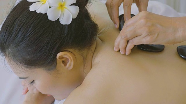 美丽的亚洲女人享受热石按摩治疗