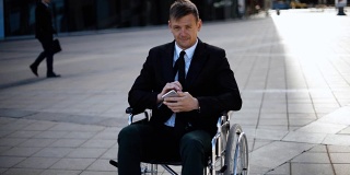 一位坐在轮椅上的年轻商人正在用他的智能手机玩或工作