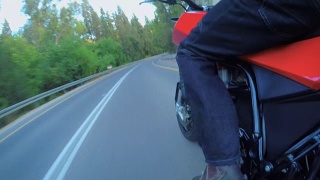 视频显示一名男子骑着一辆红色摩托车行驶在弯道上视频素材模板下载