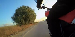 视频显示一名男子骑着一辆红色摩托车行驶在弯道上