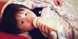亚洲女婴用奶瓶喝牛奶
