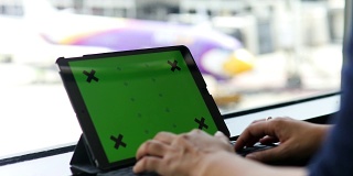 一名女子在机场使用平板绿色屏幕
