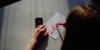 女艺术家用墨水在纸上画上鲜艳的题词，晚上在工作室里拿着艺术材料坐在桌子旁