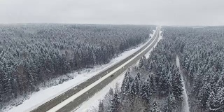 4 k。在冬天的森林里开着车在下雪。空中全景。消失点的角度来看