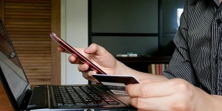 男人手持信用卡，用手机进行网上购物或电子银行