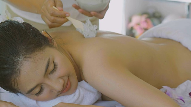 美丽的亚洲女人享受皮肤嫩肤护理与身体面膜