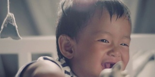 亚洲小男孩站在婴儿床上笑