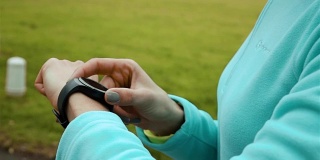 在公园里使用智能手表健身追踪器的女性跑步者