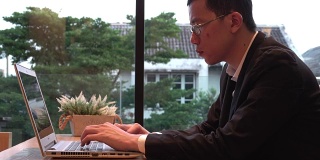4k:年轻的亚洲人在咖啡馆的电脑前工作