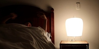 年轻人躺在床上，关掉床头柜里的灯。一个人躺着睡觉的时候在想一些事情