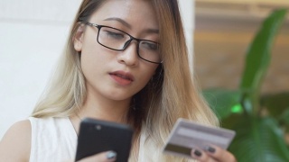 亚洲女性使用手机用信用卡进行网上购物视频素材模板下载