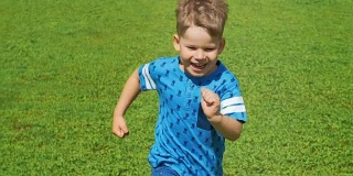 小男孩在夏天奔跑着穿过美丽的绿色田野，非常轻快和快乐的景象