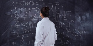年轻的学生女在黑色的黑板上解难的方程