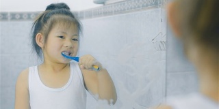 一个亚洲小女孩在浴室里刷牙