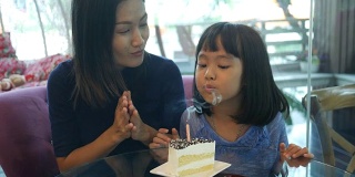 女孩和妈妈一起在咖啡店享用生日蛋糕