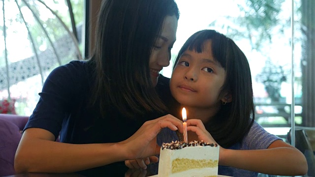 女孩和妈妈一起享用着生日蛋糕，手打心牌