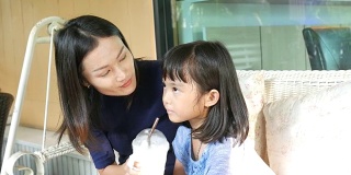 女孩和妈妈在秋千上喝奶昔