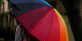 近距离观看一个开放的彩色彩虹伞在女性的手中。Slowmotion拍摄