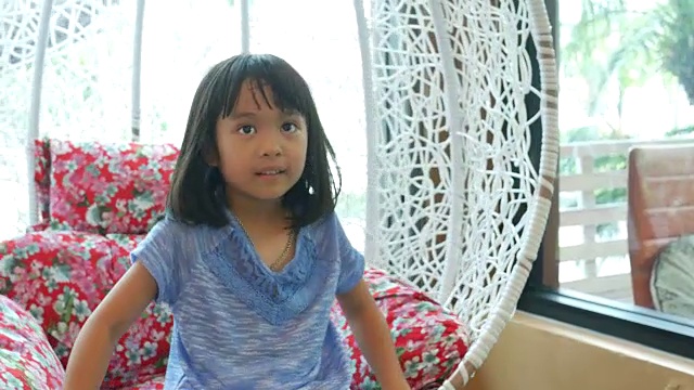 亚洲女孩在客厅的秋千上放松