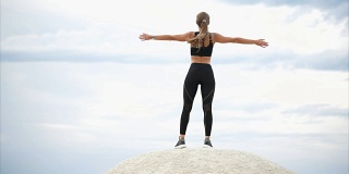 一个女人站在石头上做呼吸练习，她看向远方
