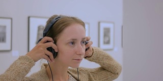 在现代照相馆里看展览和听音频导览的女人