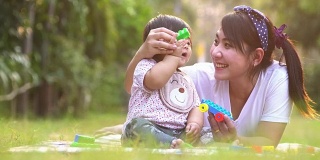 亚洲母亲和婴儿有乐趣户外。一起在绿夏公园。妈妈和孩子。幸福的家庭微笑。美丽的家庭在春天的公园享受大自然。