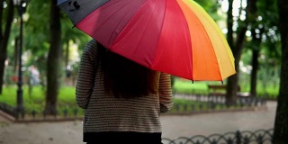 一个不认识的女人在雨下跑在城市公园的背影。Slowmotion拍摄