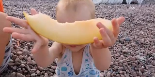小男孩在海滩上吃瓜