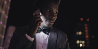 年轻的非洲商人站在城楼上用智能手机拨打电话交谈