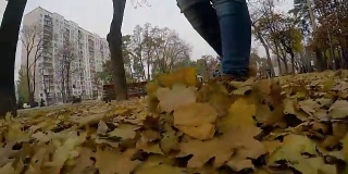 孤独的女人走过秋天的公园，扬起金色的落叶