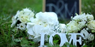 婚礼装饰字爱，鲜花和木质牌匾与字母D和M在公园的绿草背景